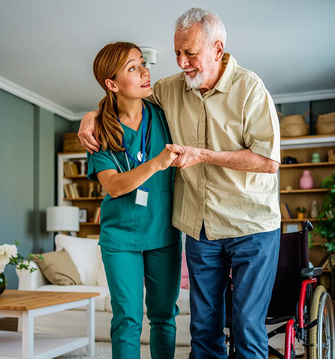 Caregiver assisting elderly man at home.