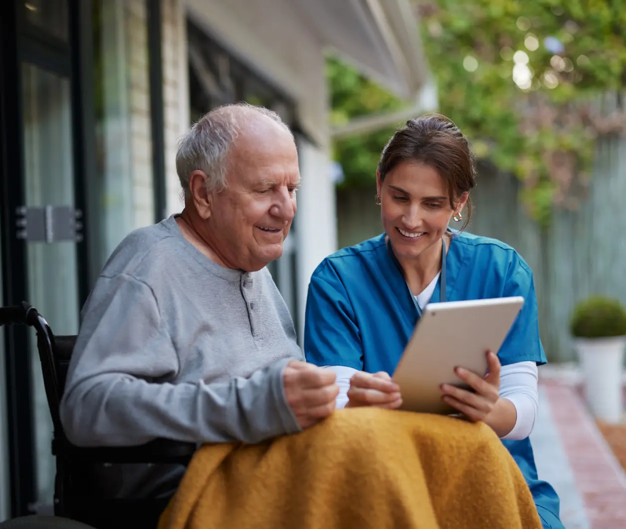 Elderly man and nurse with tablet outside.