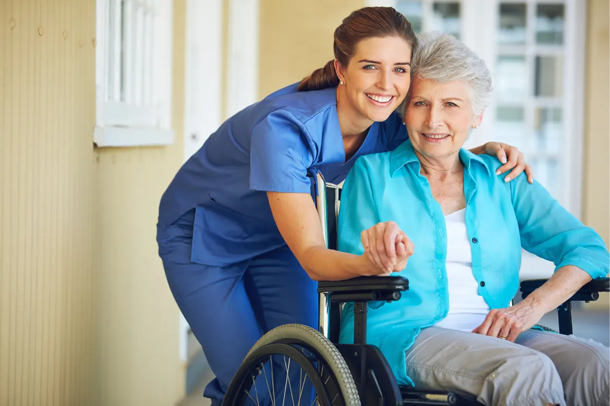 Nurse smiling with elderly woman in wheelchair.