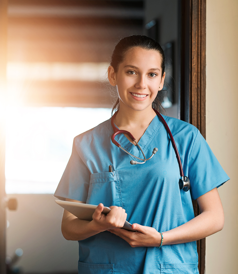 Smiling nurse holding a tablet indoors.