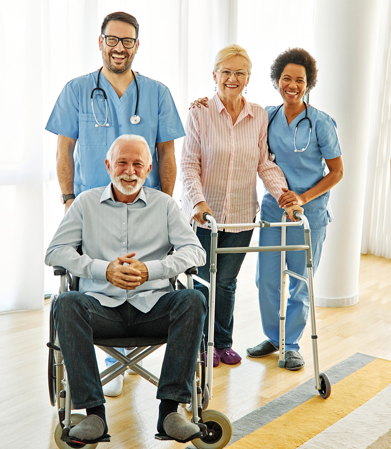 Elderly couple with medical staff smiling.