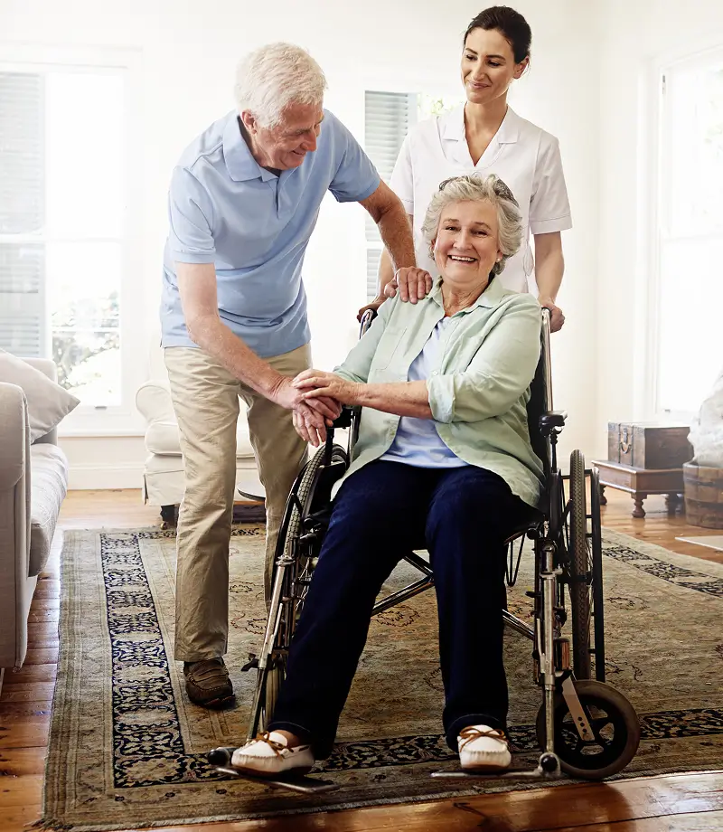 Elderly woman in wheelchair with caregivers.